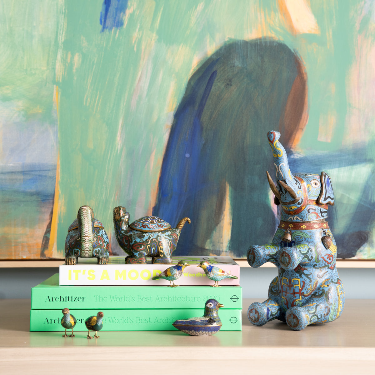 Decorative elephant figurine on books with a colorful abstract painting in the background