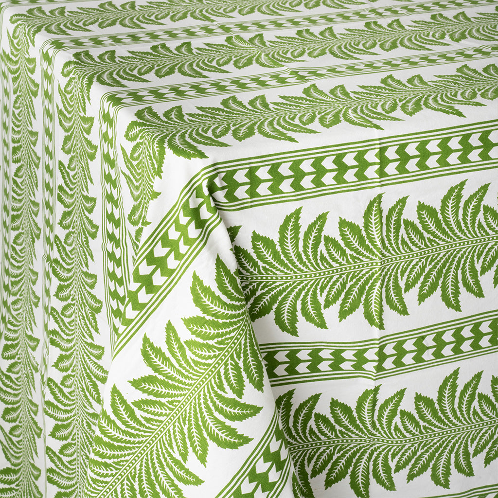 close up image of a green and white tablecloth with palm tree pattern, draped over a table, on a white background