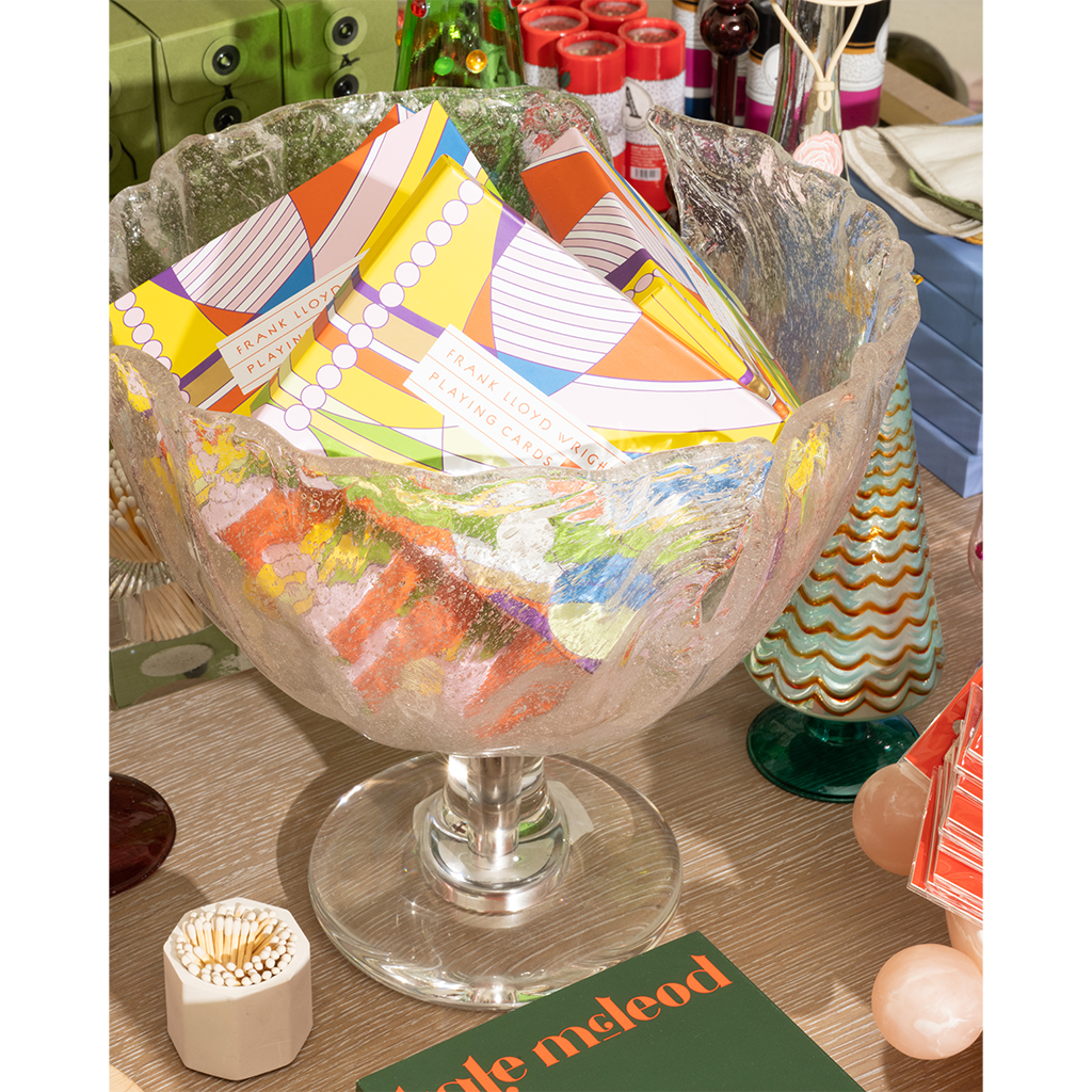 Decorative glass bowl filled with colorful cards on a table.