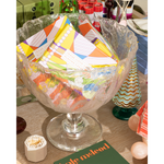 Decorative glass bowl filled with colorful cards on a table.