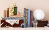 Collection of books, a golf ball, and decorative items on a surface with a neutral background.