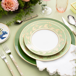 Green and gold floral patterned china in a table setting with floral arrangement