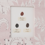 Three black oval stamps on a white card with text, set against a pink floral patterned background.