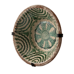 A rustic ceramic mixing bowl with a distressed brown rim, decorated with green hand-painted floral and wavy patterns on a cream-colored interior. The bowl is shown suspended by black straps against a plain white background.
