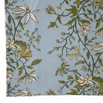 close up image of a blue and green botanical tablecloth on a white background