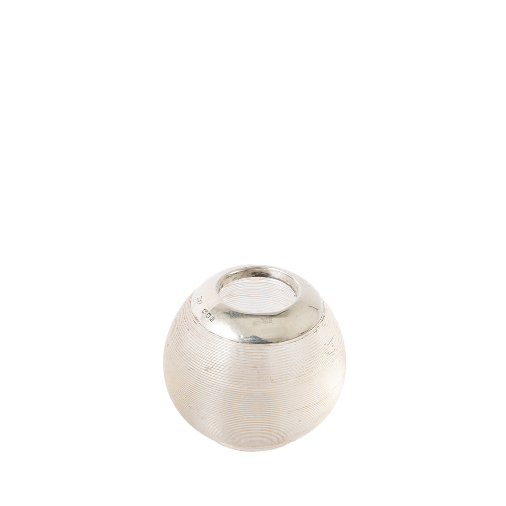 A small silver-toned metal container or cap with a ribbed textured body and a smooth circular top, photographed on a plain white background.