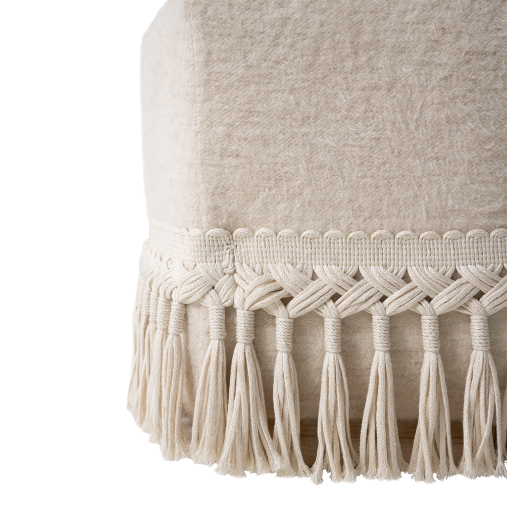 Close-up of a textured fabric with macrame tassels on a white background