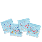 Four light blue square napkins with scalloped edges, each printed with a small beach scene featuring people, umbrellas, chairs, and towels, arranged on a white background.