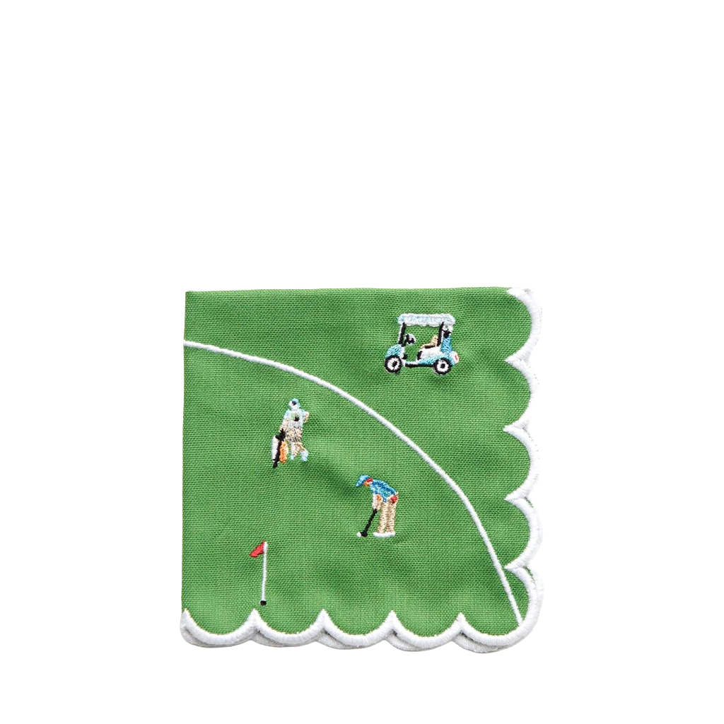 A square green napkin with scalloped white edges, featuring embroidered golf course details including a golfer, golf cart, flag, and white tees on a white background.