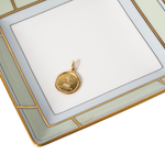 Gold pendant on a white tray with decorative gold border