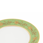 Close up of a green decorative dinner plate with gold leaf pattern on a white background