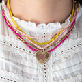 yellow and baby pink corded necklace stacked with other jewelry