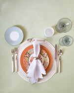 place setting with colorful plates and notched linen napkin