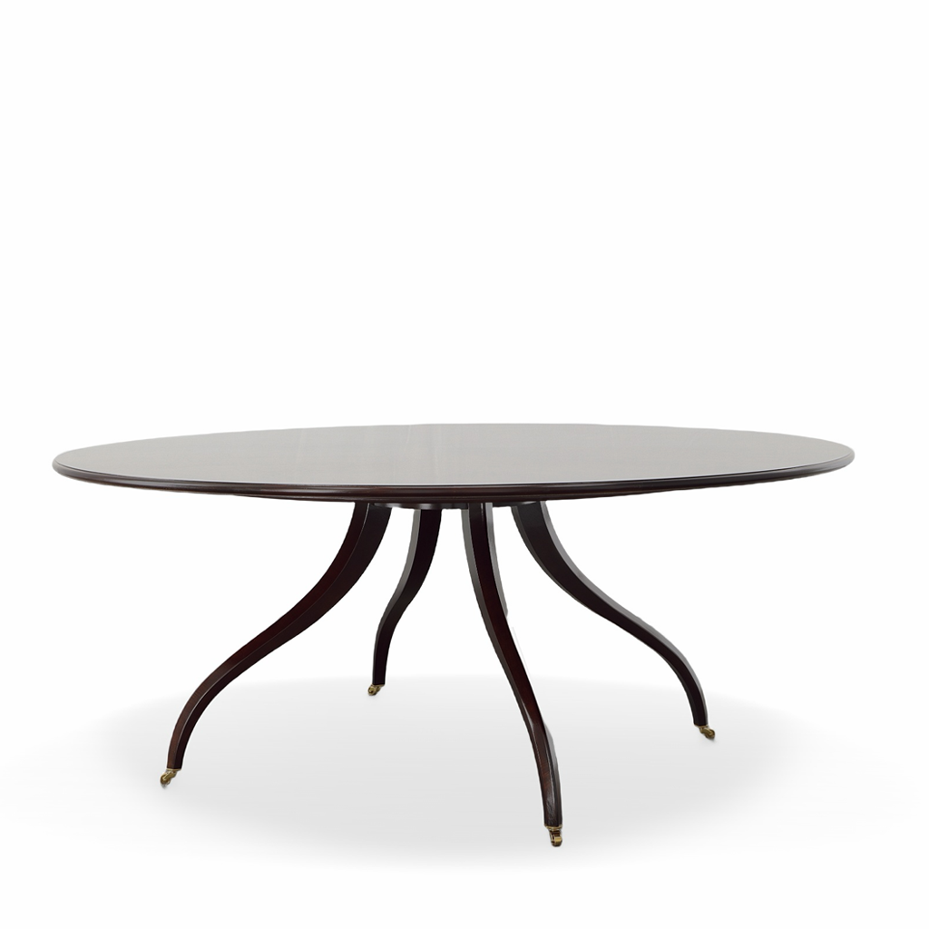 Elegant oval dining table featuring a smooth, dark mahogany finish and a slim tabletop with a gently rounded edge. The sculptural pedestal base features four gracefully curved legs with delicate brass-capped feet, creating a timeless, sophisticated silhouette.
