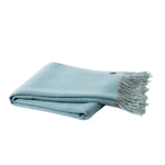 A folded light blue throw blanket with fringed edges, displayed on a clean white background.