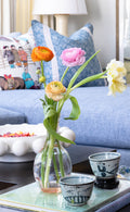 coffee table with vase filled with flowers, cups and books