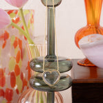 Heart necklace dangling from a green glass candleholder