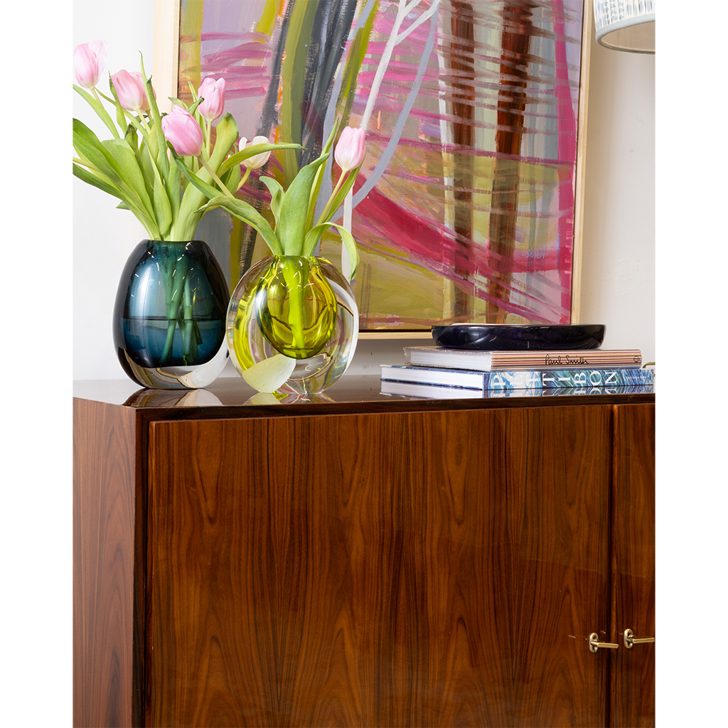 Decorative scene with colorful vases and tulips on a wooden cabinet.