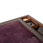 Close-up of a wooden box interior with a purple felt playing surface and a small divided storage compartment, photographed on a white background.