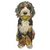 A sculptural art piece of a dog made from mixed materials, featuring a black and white fluffy face with a bright green ball in its mouth, set against a plain white background.
