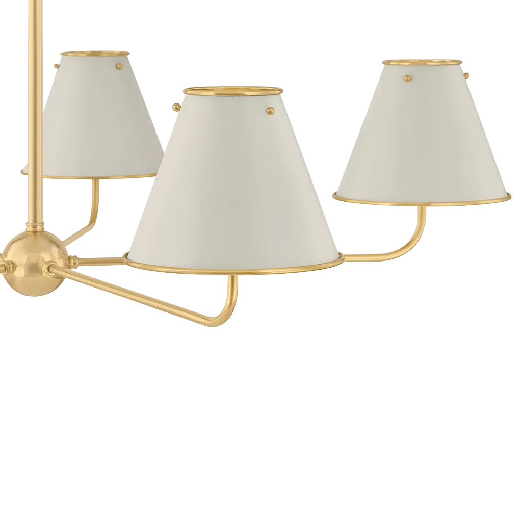A close up of a five-light chandelier with a polished gold-finished metal frame and tapered off-white fabric shades, shown against a plain white background.