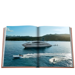Open book showing a scenic view of a yacht on the water with mountains in the background.