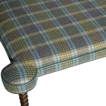 Plaid-patterned fabric on a piece of furniture with wooden legs.