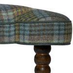 Close-up of a plaid ottoman with wooden legs on a white background
