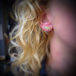 Close-up of an ear wearing a diamond earring with blurred background