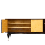 French mid-century modern lacquered sideboard, in the manner of Jacques Adnet. Rectangular case fitted with two sets of dual cabinet doors, one side opening to two drawers, and storage compartment, mirrored bottom panel, interior lighting in need of wiring, opposite side opening to two shelves, case rising on tapered legs ending on brass feet.