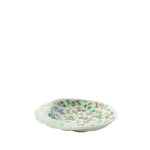 A small oval ceramic dish with a scalloped rim, decorated with a delicate multicolor floral pattern on a white background, isolated on a white studio background.