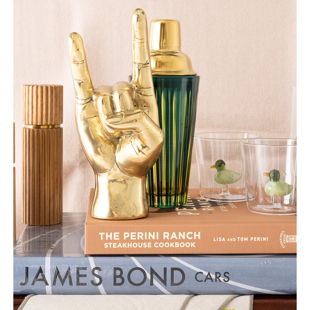Decorative items including a gold hand-shaped object, cocktail shaker, and books on a surface.