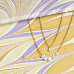 Gold necklace with small diamonds on a decorative yellow and purple background