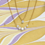Gold necklace with clear stones on a yellow and purple patterned background