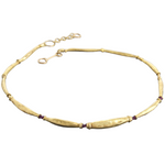 Gold necklace with purple beads on a white background