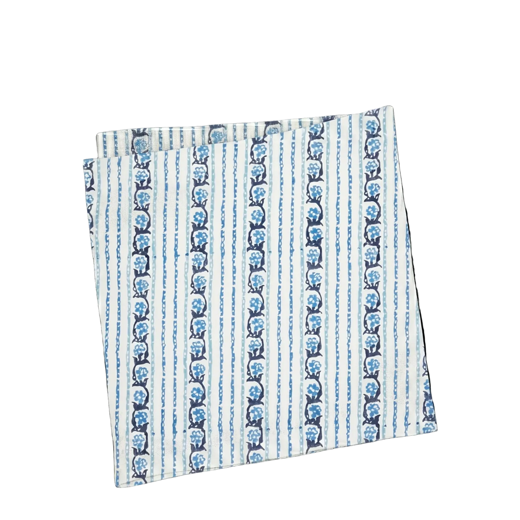 A folded square napkin featuring a vertical striped pattern in blue and navy on a white background.