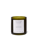 A Flaming Estate 'Sappho Fig' scented candle in a dark olive-green glass jar with a white paper label, set against a plain white background.