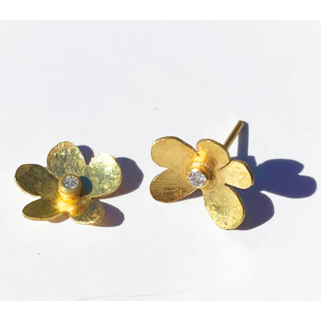 Gold flower-shaped earrings with diamond stud on a white background