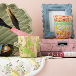Decorative items including a green woven basket, colorful ice bucket, blue frame, and pink box on a pink surface.