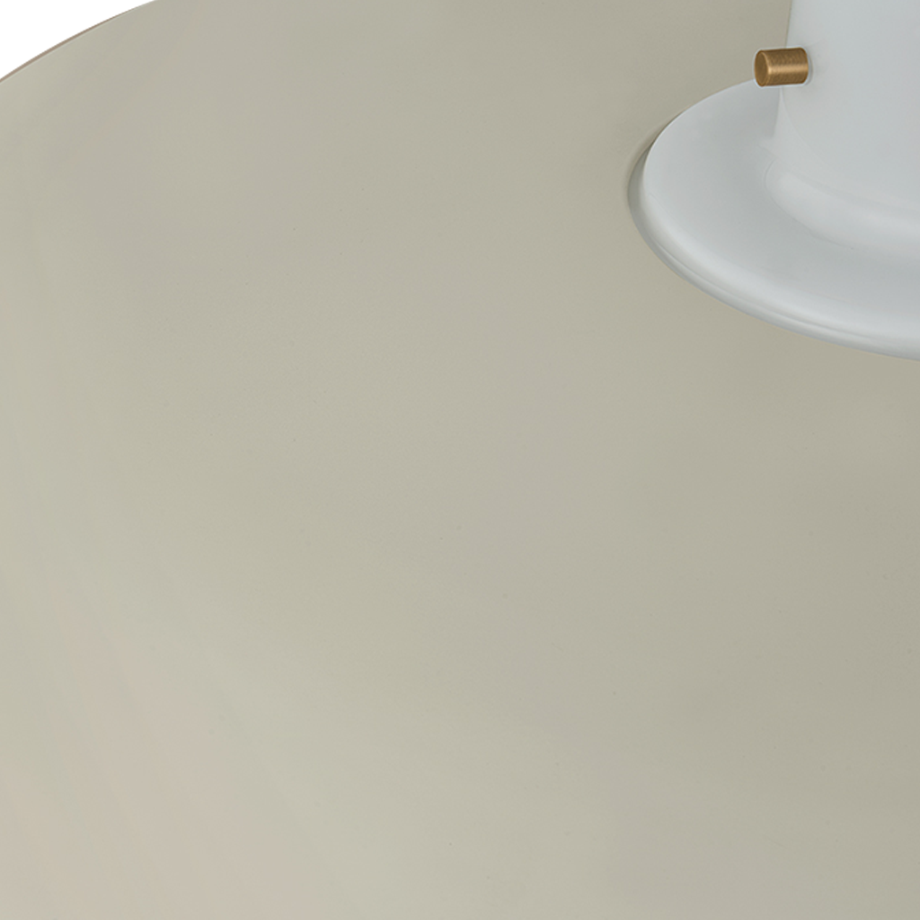Close-up detail of a light fixture showing a large matte beige shade, a white circular base, and a small brass-toned accent.
