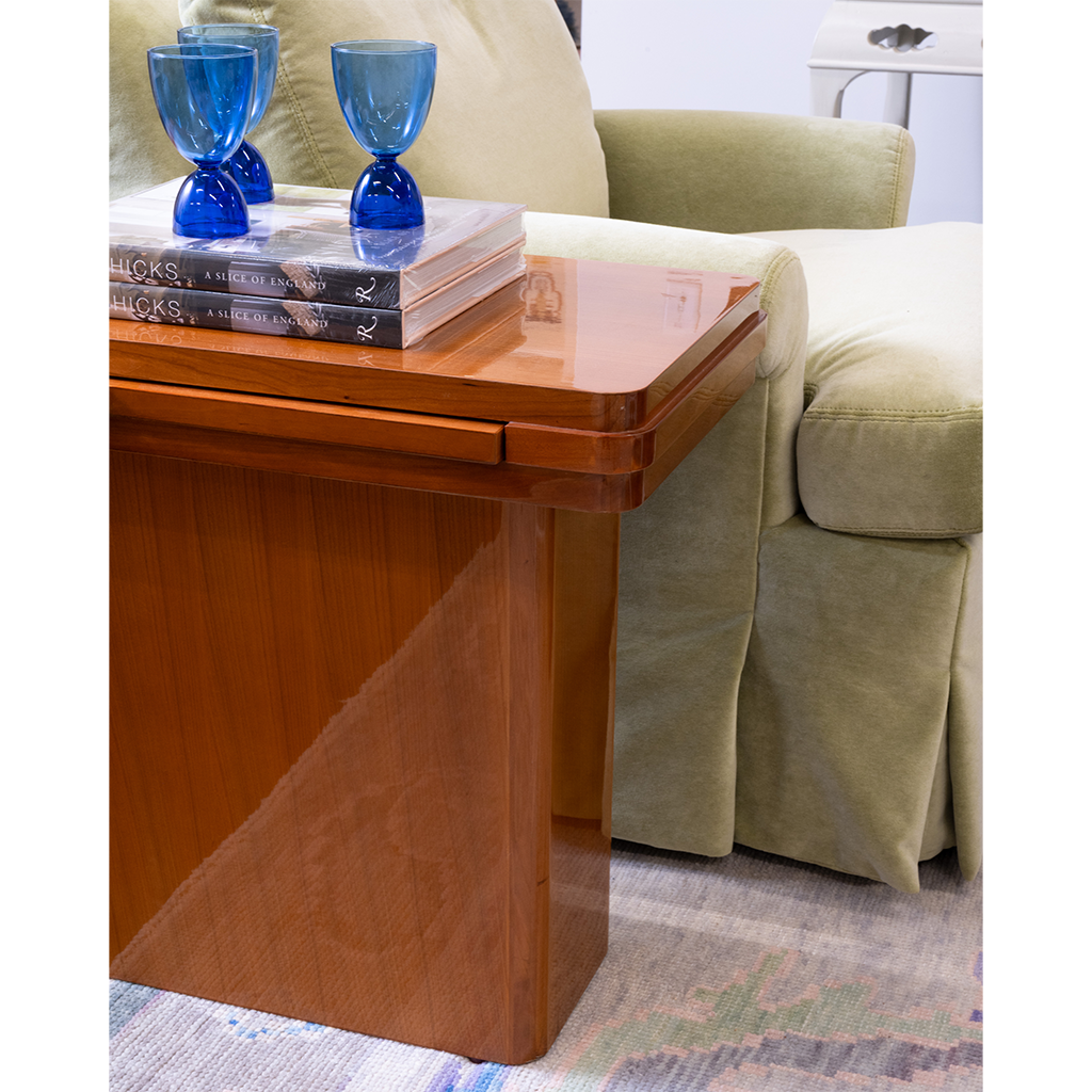Wooden side table with blue glass goblets and books next to a beige armchair.