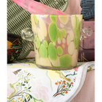 Decorative ice bucket with green and white design on a table with a colorful tablecloth.