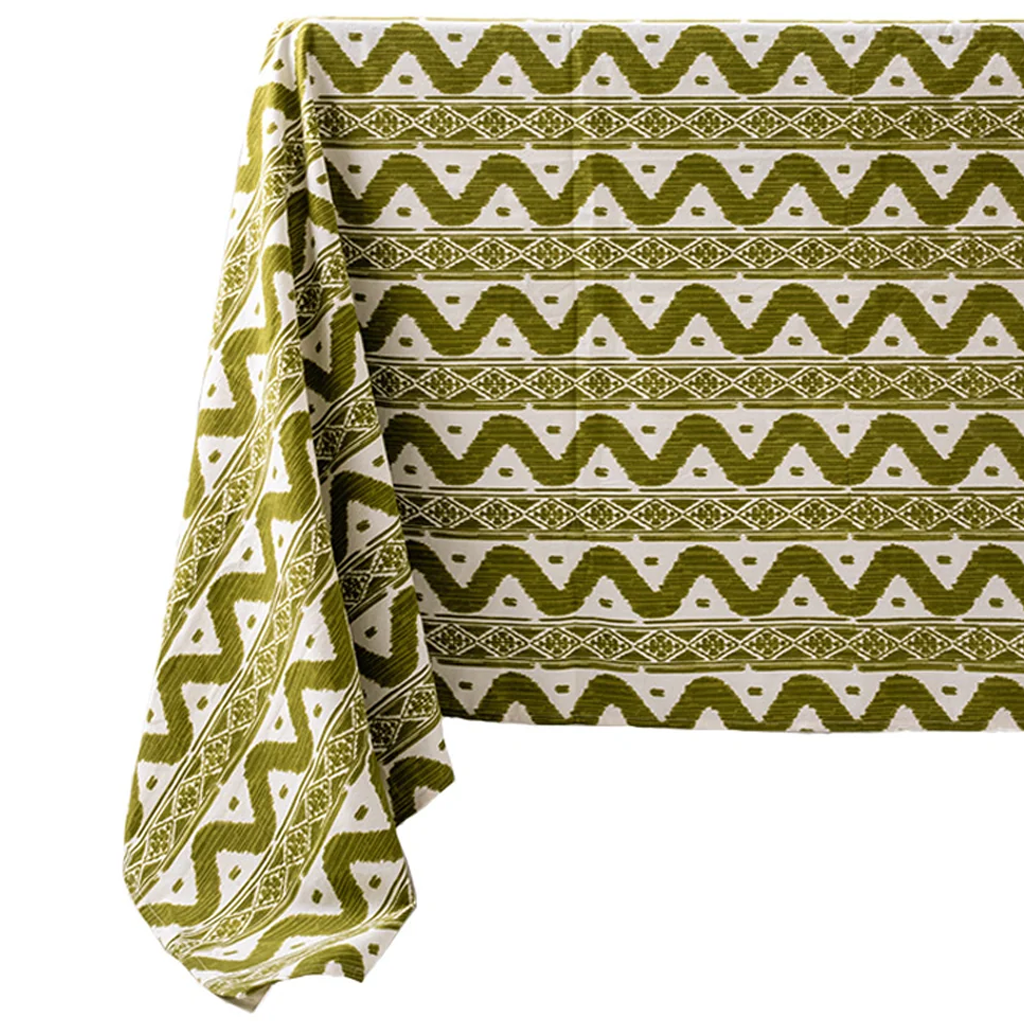 A tablecloth with a bold olive green and white geometric ikat pattern, draped to show its texture and design on a clean white background.