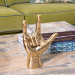 Gold hand sculpture on a coffee table with books in the background
