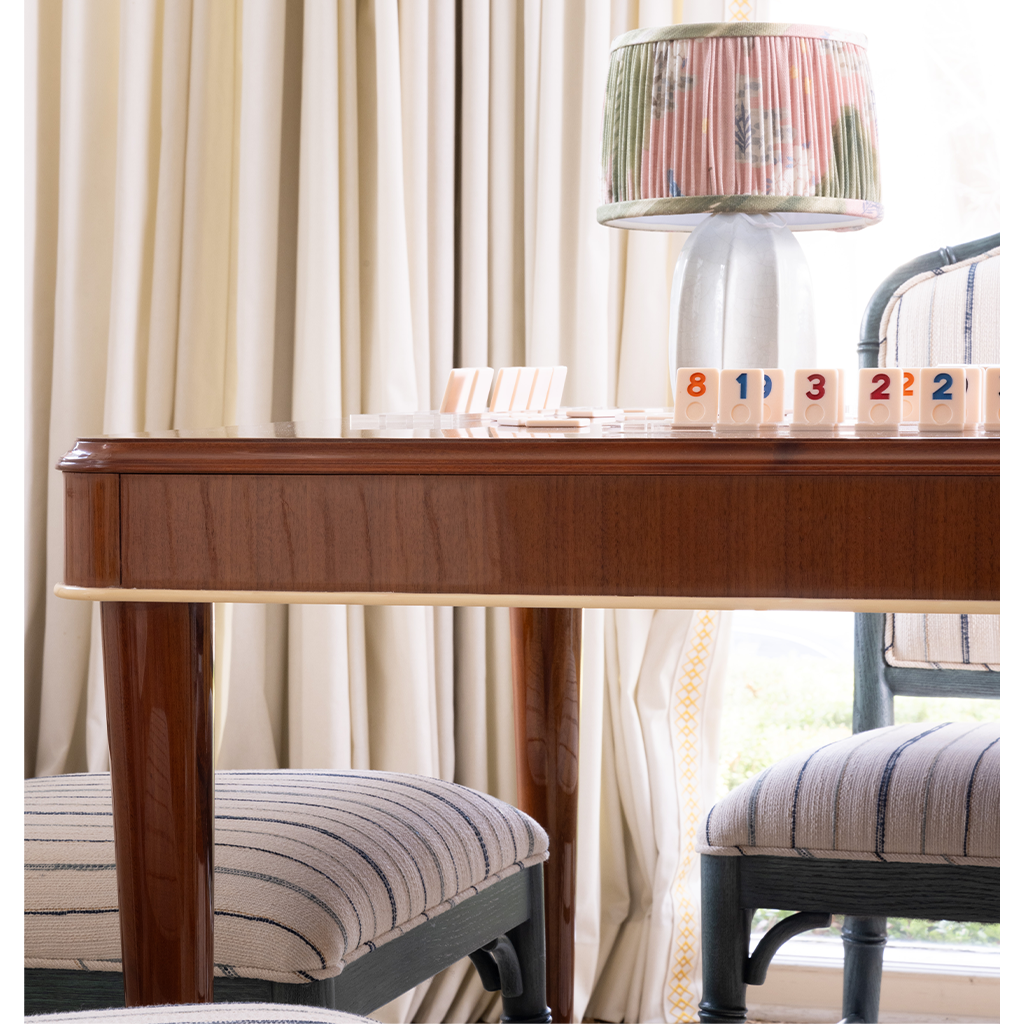 Wooden game table with striped chairs and a lamp in a room with curtains