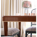 Wooden game table with striped chairs and a lamp in a room with curtains