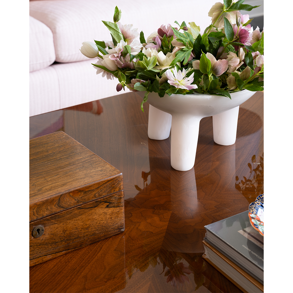 Floral arrangement in a white bowl on a wooden coffee table
