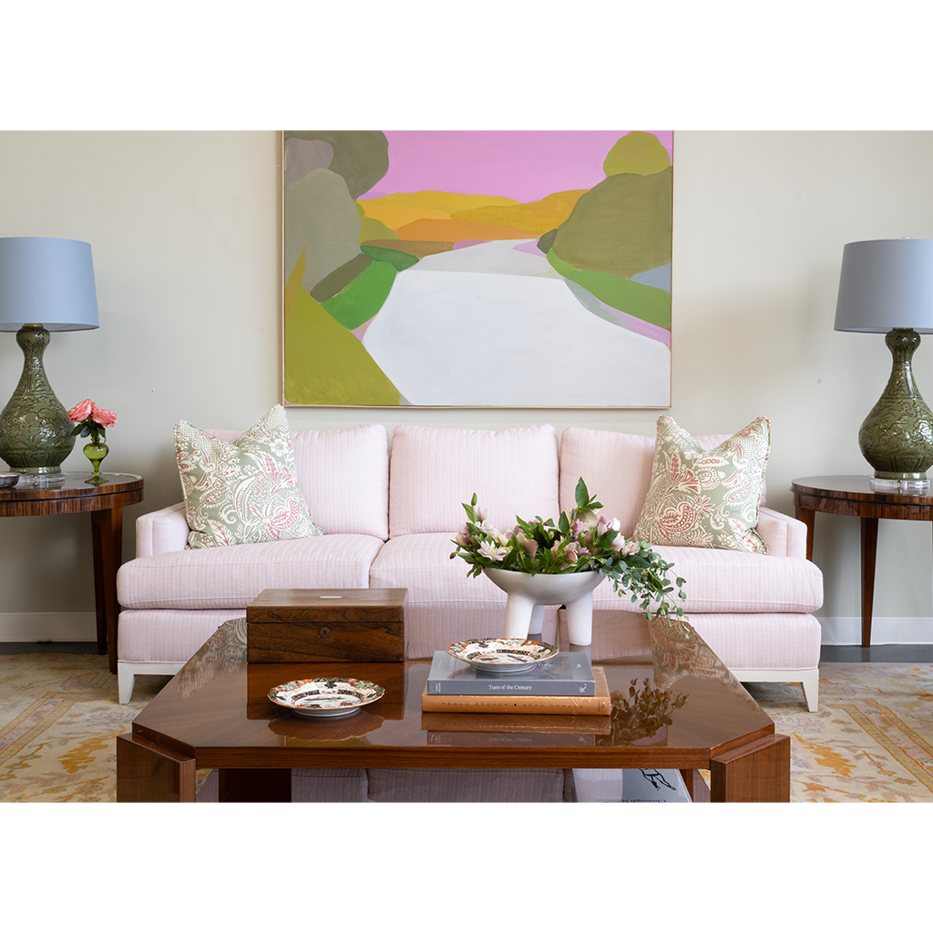 Living room with a pink sofa, coffee table, and decorative elements.