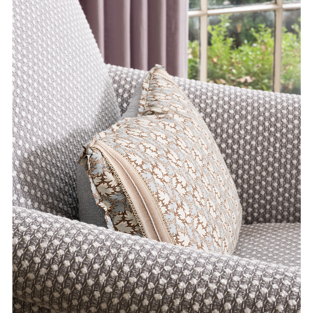 Patterned pillow on a textured sofa with a blurred outdoor background