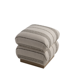 A square ottoman with a textured beige fabric upholstered cushion stacked on a light wood base, featuring thin black dotted stripe patterns, shown on a plain white background.